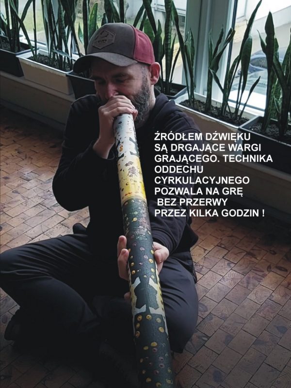 Postać siedząca gra na didgeridoo