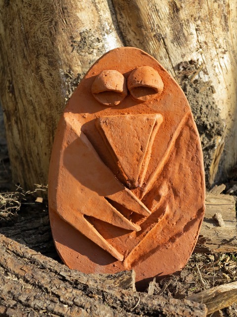 figurka sowy z wypalonej gliny w naturalnym leśnym otoczeniu