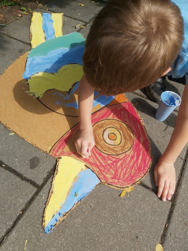 Chłopiec maluje na chodniku sylwetę wyciętego ptaka