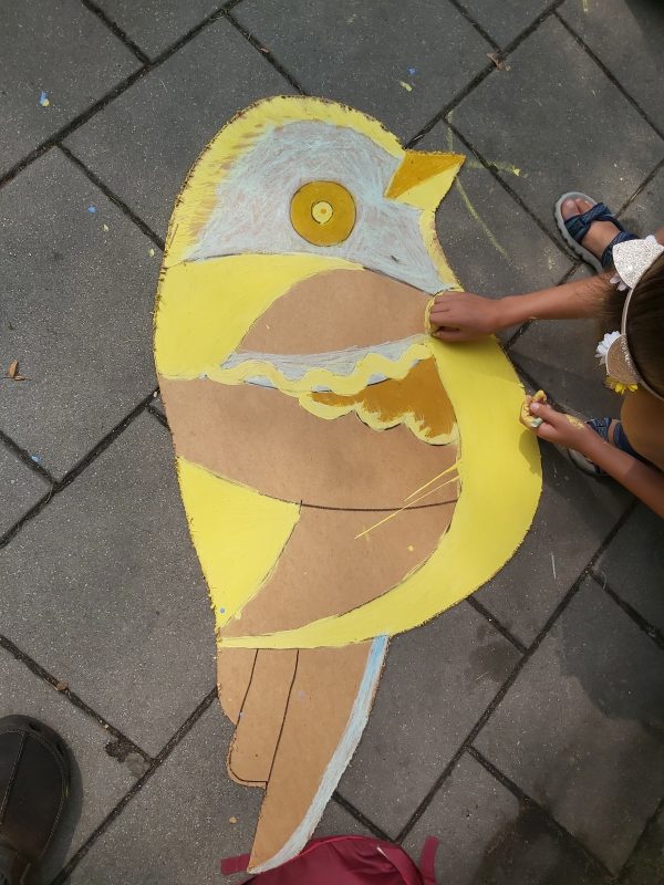 Dziewczynka maluje sylwetę wyciętego ptaka na chodniku