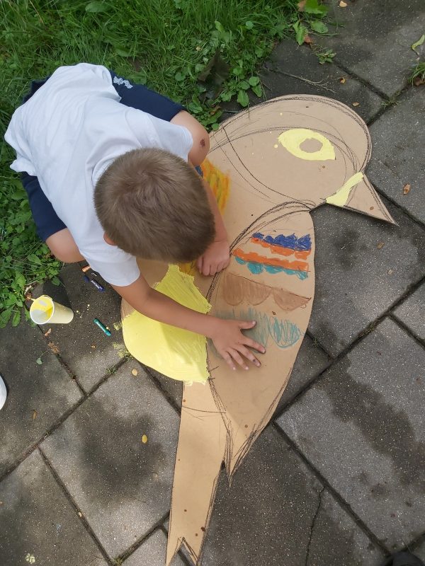 Chłopiec maluje na chodniku sylwetę wyciętego ptaka