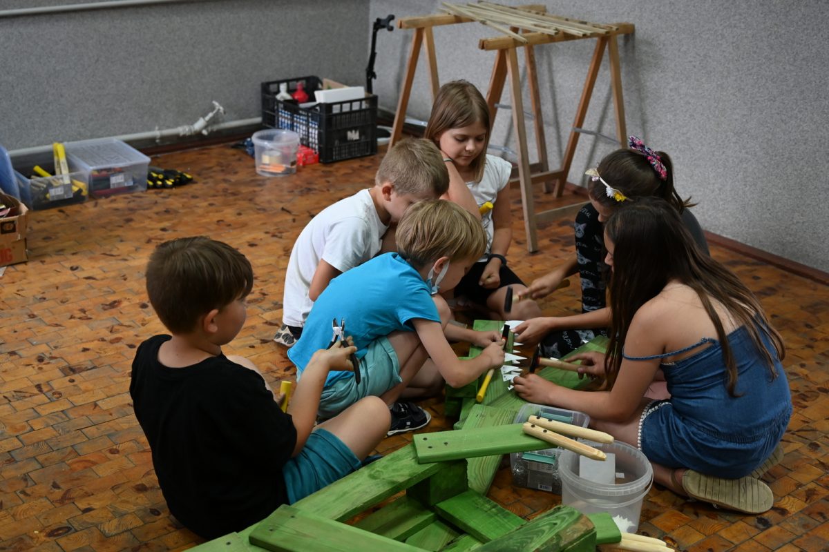 Grupa dzieci na podłodze przy montażu zębów dinozaura