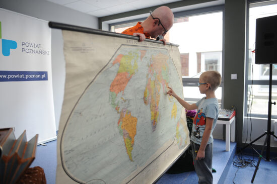 Na mapie trzymanej przez aktora chłopiec pokazuje gdzie leżą Indie.
