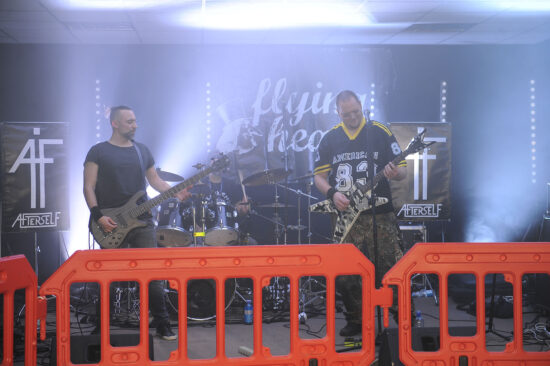 Gitarzyści na scenie za barierkami.