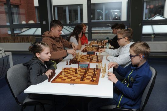Młodzi szachiści przy stole, szachownice, zegary