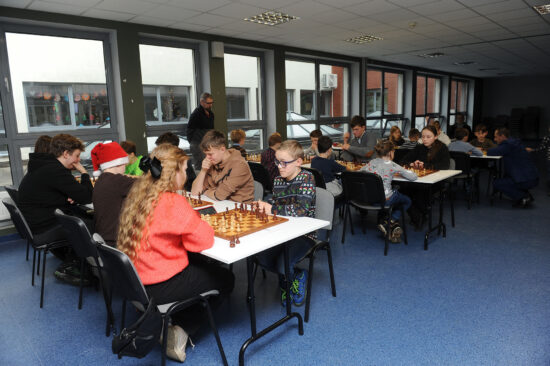 Młodzi szachiści przy stole, szachownice, zegary