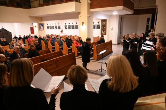 Śpiewające chórzystki. W tle publiczność w ławkach kościelnych