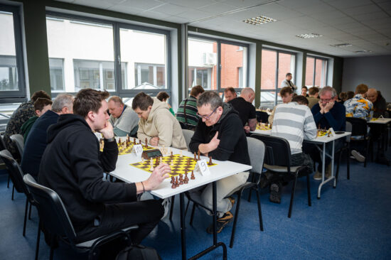 Starsi szachiści przy stole, szachownice, zegary.