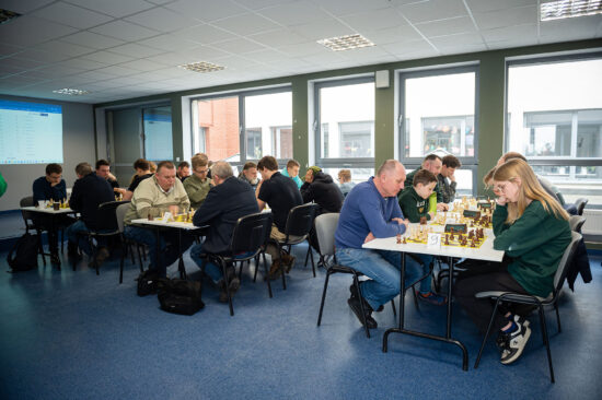Starsi szachiści przy stole, szachownice, zegary.