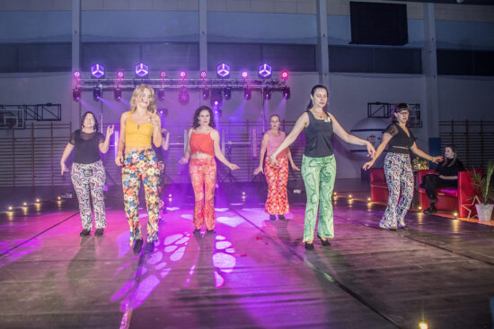 Grupa tańczących kobiet w kolorowych strojach.