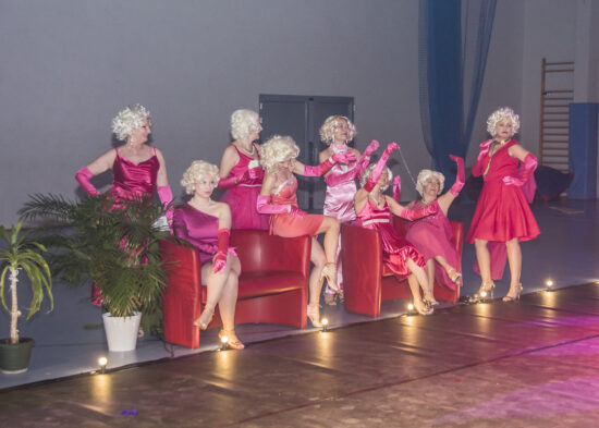 Grupa tańczących kobiet w różowych strojach.